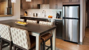 Una cocina moderna con armarios de madera oscura, un refrigerador de acero inoxidable y una isla central con asientos.