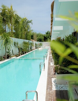 A swimming pool with a clear blue water, surrounded by greenery and a white building. - Baliterraneo Boutique Resort Seminyak (Seminyak)