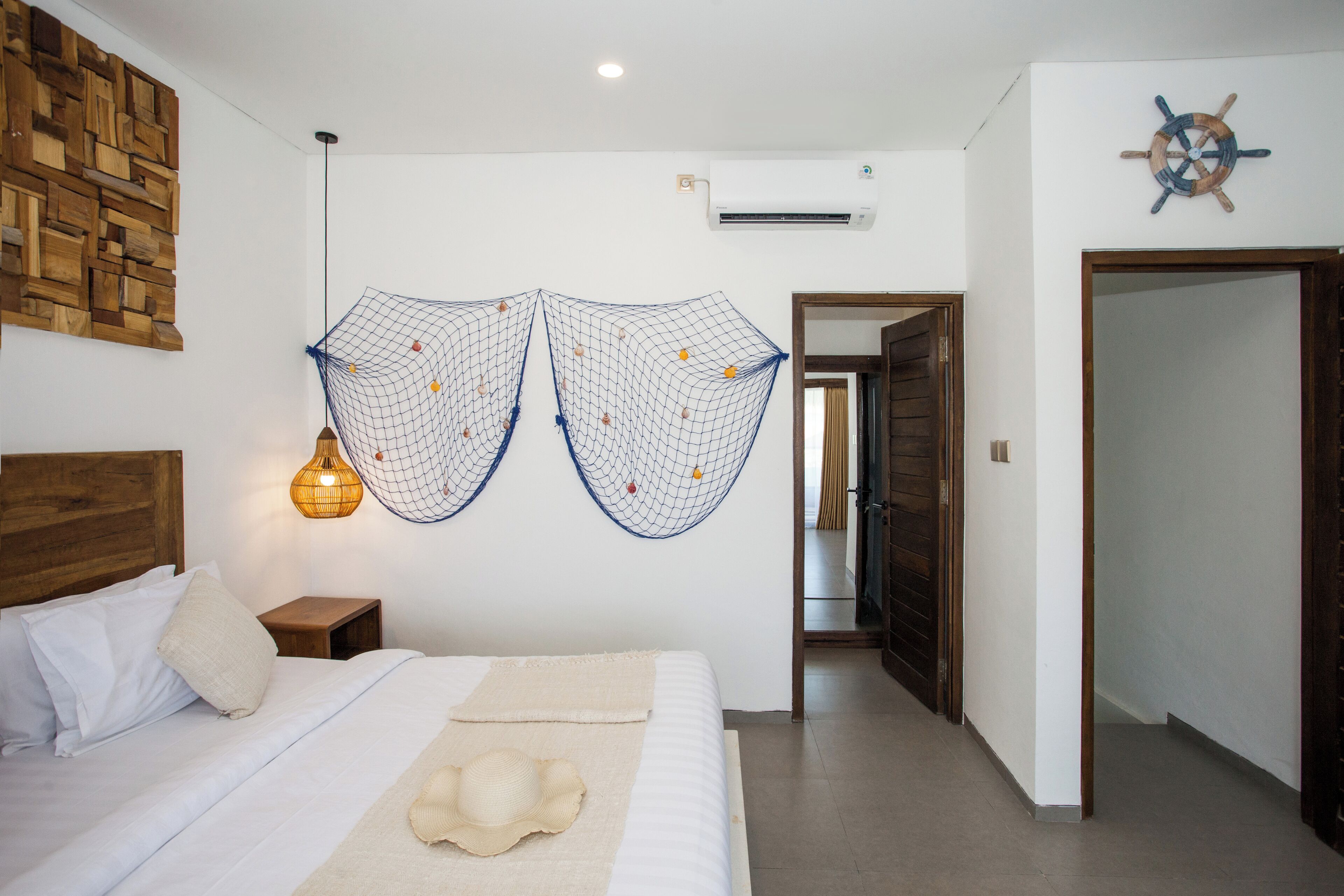 Camera da letto con una testiera in legno, un letto con biancheria bianca, una decorazione a rete sospesa e un condizionatore d'aria a parete.