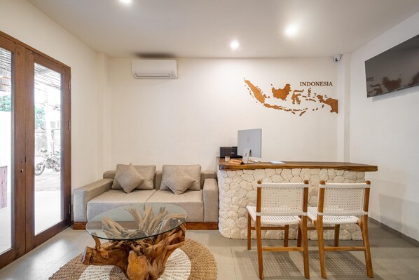 A modern living area with a stone reception desk, a glass coffee table, a sofa with cushions, and wicker chairs. - Baliterraneo Boutique Resort Seminyak (Seminyak)