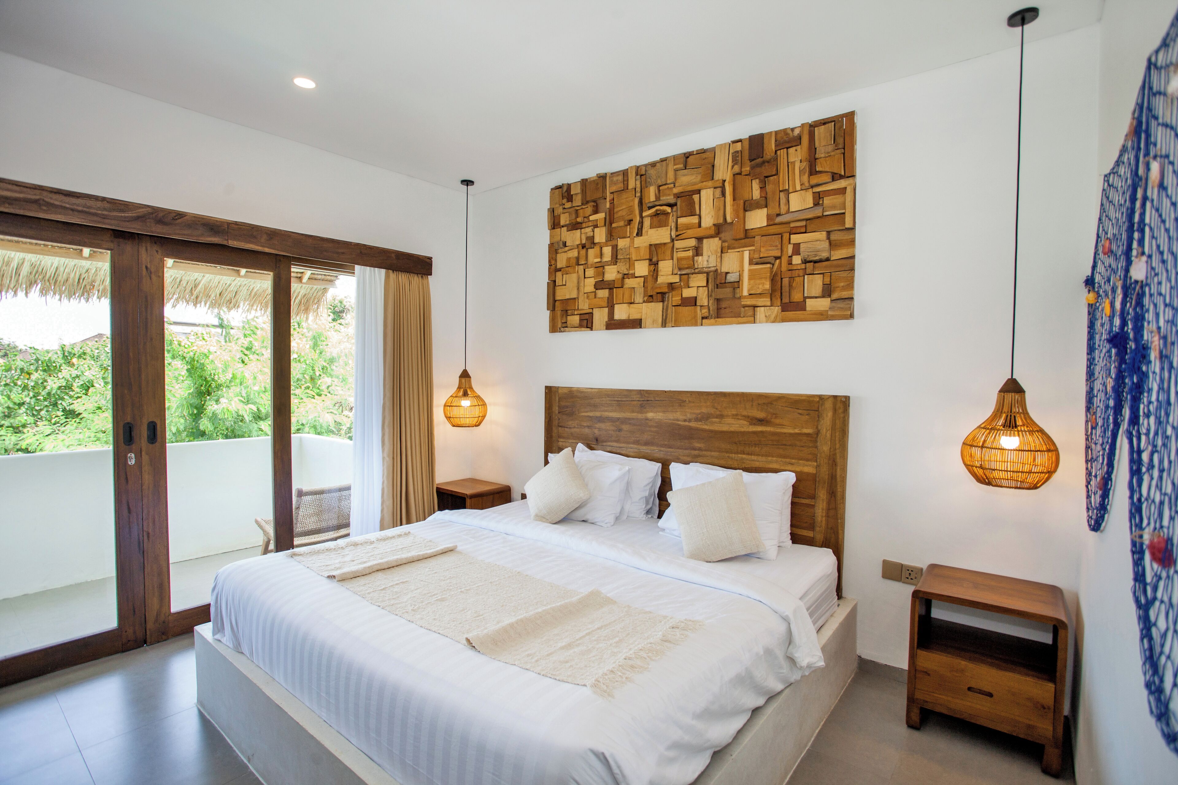 A bedroom with a large bed, wooden headboard, and a wall-mounted light fixture.