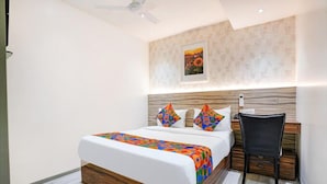 A modern bedroom with a wooden bed frame, a nightstand, and a chair. - Glitz Hotels DR Residency (Mumbai)