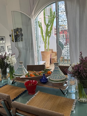 Un comedor con una mesa preparada para dos, con un cactus, naranjas y jarrones decorativos.