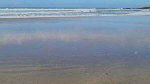 A beach with waves, clear sky, and distant rocky outcrops. - DAR INES TANGIER (Tangier)