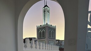 Un escalier menant à une mosquée dotée d’un minaret, le tout entouré d’un mur blanc et d’une rambarde en métal.