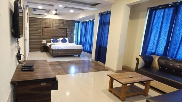 A modern hotel room with a bed, a desk, a sofa, and a TV. - Pheonix By Glitz Hotels (Panvel)