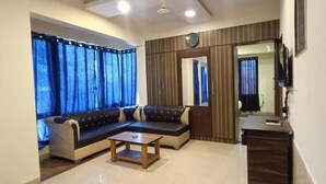 A living room with a sectional sofa, a coffee table, and a TV. - Pheonix By Glitz Hotels (Panvel)