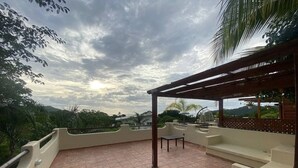 A rooftop terrace with a pergola, seating, and a view of the surrounding landscape. - Magical Sunsets at Coco Sunset Hills (Playas del coco)