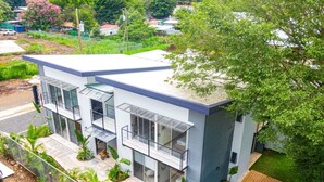 A modern two-story house with a swimming pool, large windows, and a fenced yard. - Brand New Condo - Heart of Coco! (Coco)