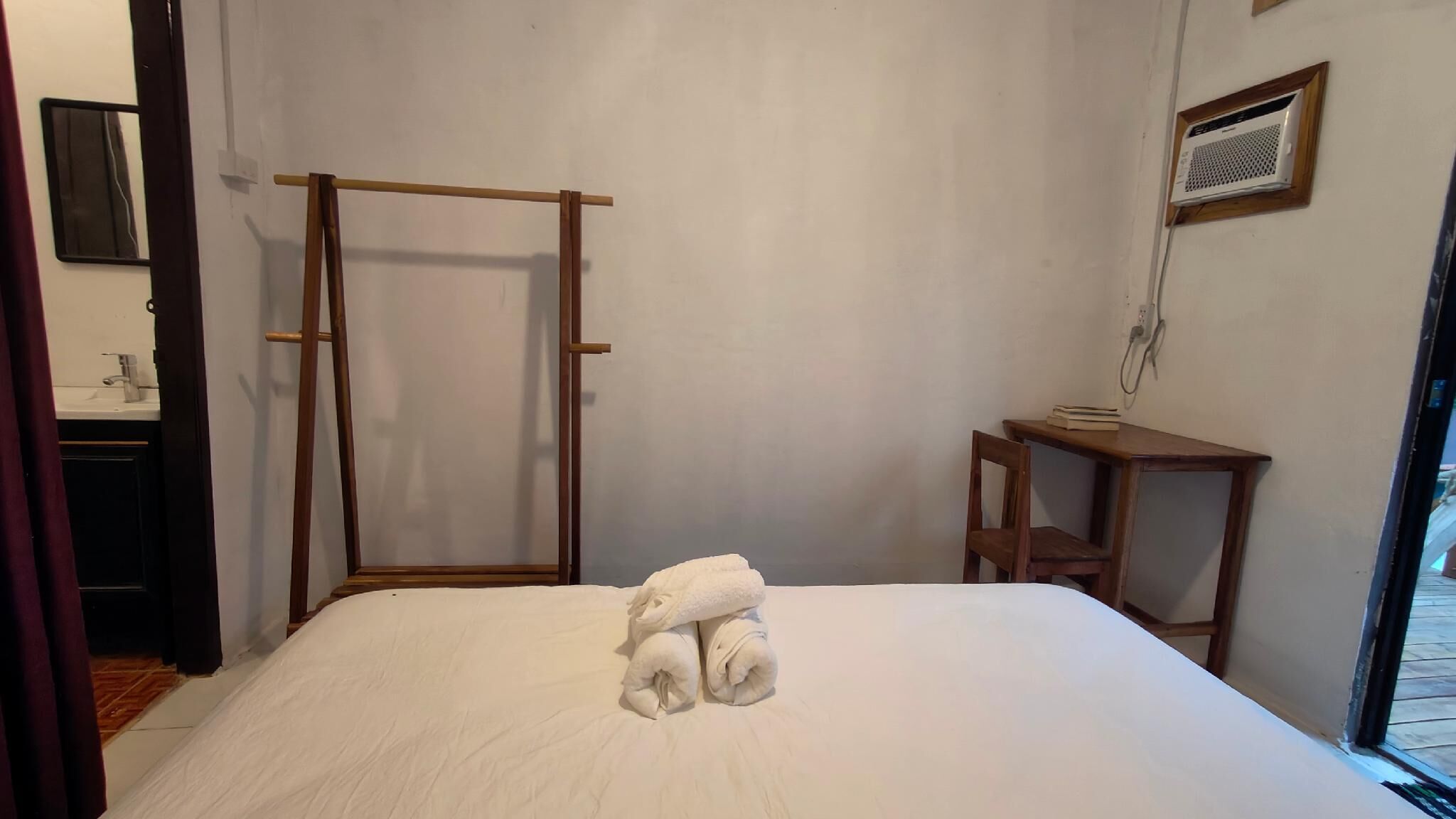 A bedroom with a bed, a wooden ladder, a small table, and a window.