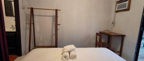 A bedroom with a bed, a wooden ladder, a small table, and a window.