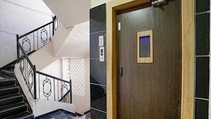 A staircase with a metal railing and a wooden door with a small window. - PS By Glitz Hotels (Navi Mumbai)
