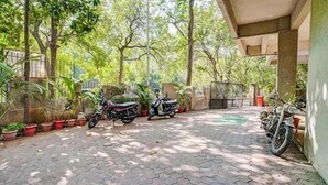 A paved courtyard with potted plants and two motorcycles parked. - PS By Glitz Hotels (Navi Mumbai)
