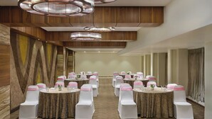 A conference room with round tables, white chairs with pink sashes, and modern chandeliers. - The Fern Residency Ahmedabad, Ellisbridge, Series by Marriott (Ahmedabad)