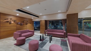 A modern lobby with plush seating, a glass coffee table, and a wooden accent wall. - The Fern Residency Ahmedabad, Ellisbridge, Series by Marriott (Ahmedabad)