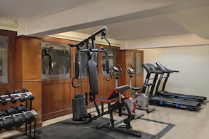 Un gimnasio con máquinas de pesas, mancuernas y cintas de correr.