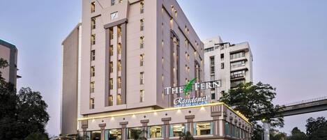 A modern hotel with a prominent sign, multiple floors, and a parking area.