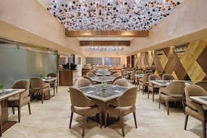 Un comedor amplio con varias mesas y sillas, un techo decorativo y un diseño de interiores moderno.