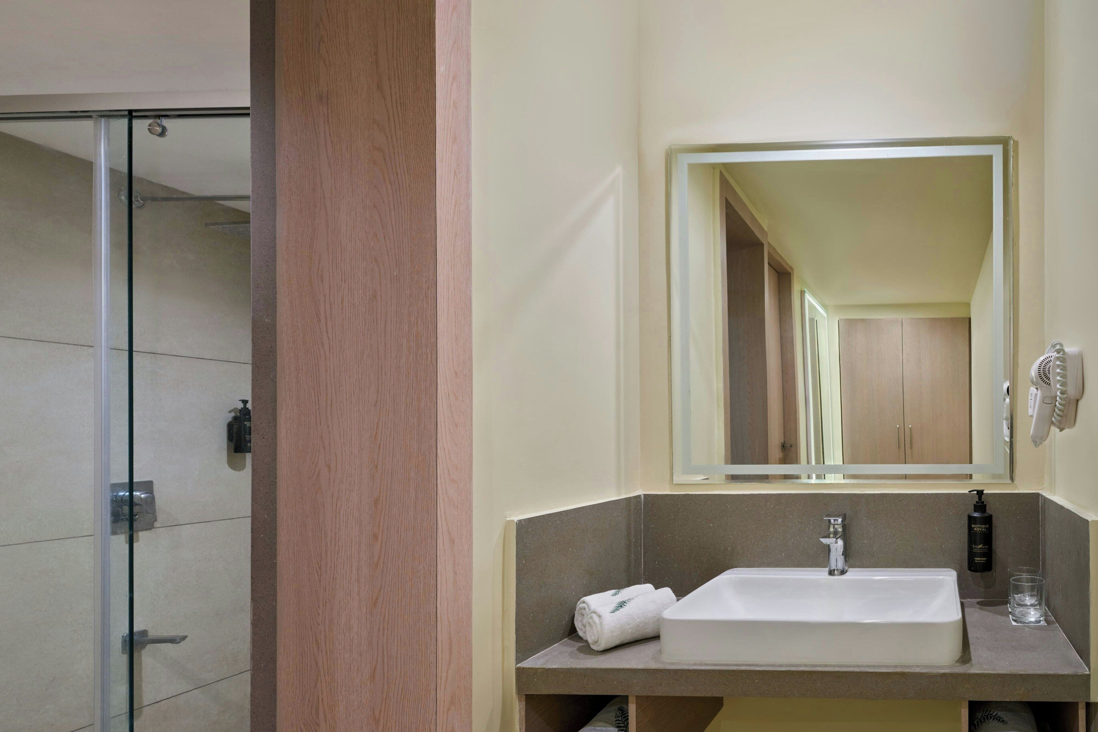 A bathroom with a glass shower, a sink with a mirror, and a towel.