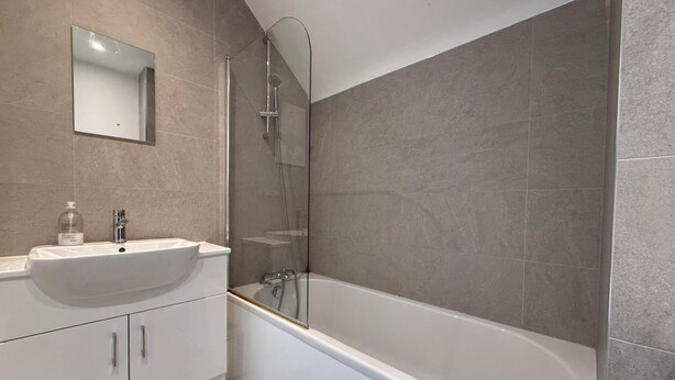Ein modernes Badezimmer mit einer freistehenden Badewanne, einer separaten Duschkabine und einem Waschtisch mit Spüle und Spiegel.