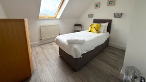 Ein Schlafzimmer mit einem Bett, einem Oberlicht, einer Heizung und einem Holzboden.