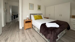 Ein Schlafzimmer mit einem Bett, Nachttischen, einem Kleiderschrank und einer Tür zu einem Badezimmer.