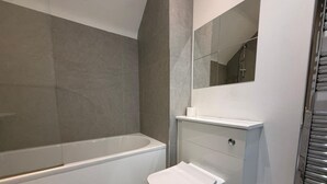 Ein Badezimmer mit einer Badewanne, Toilette und einem Spiegel.