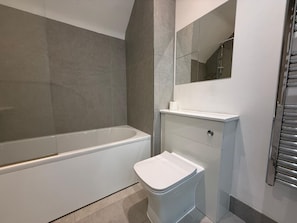 Ein Badezimmer mit einer Badewanne, Toilette und einem Spiegel.