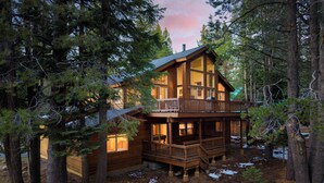 A two-story log cabin with a balcony, surrounded by tall pine trees. - Hansel by AvantStay | Pool Table, 5mins to Skiing (Truckee)