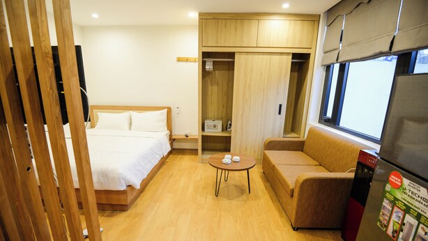 Ein Hotelzimmer mit Bett, Sofa, kleinem Tisch, Kleiderschrank und Kühlschrank.
