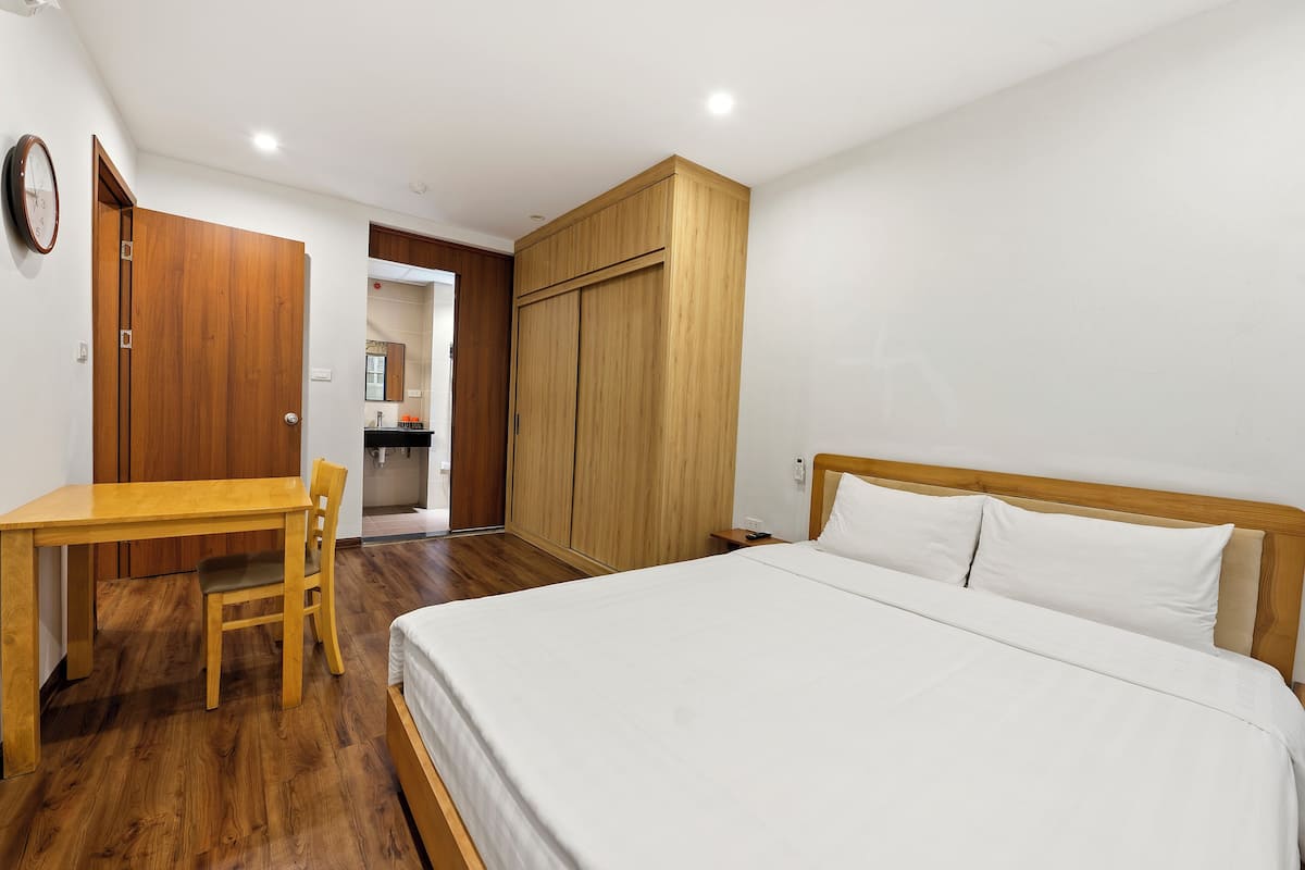 Une chambre à coucher avec un lit en bois, un bureau en bois et une armoire.