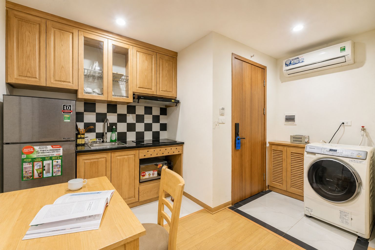 A compact kitchen with wooden cabinets, a built-in oven, a sink, and a washing machine.