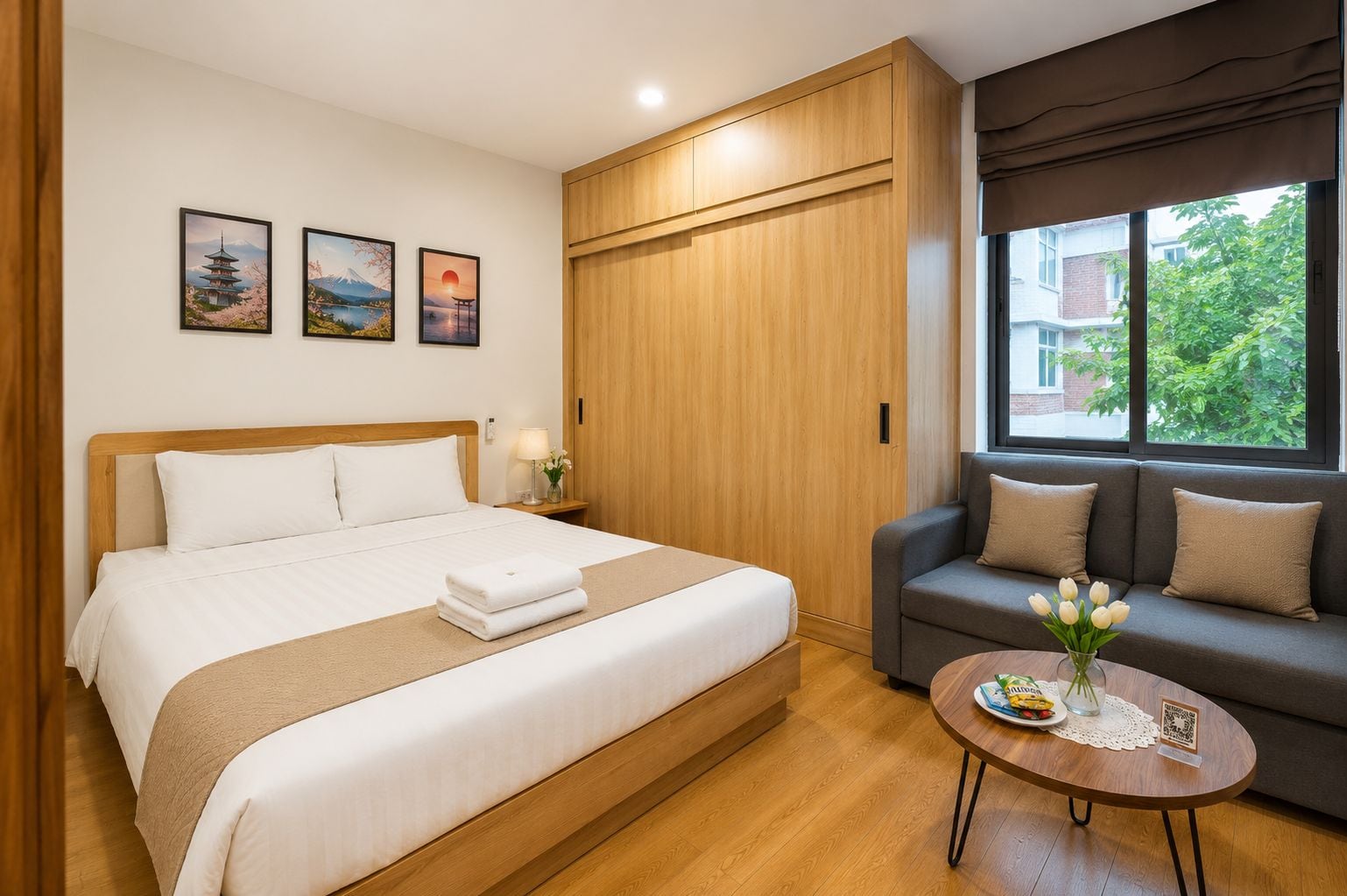 A hotel room with a bed, a sofa, a round table, and a window with a view.