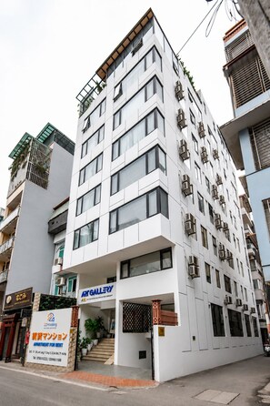 Un immeuble à plusieurs étages doté d’une architecture moderne, caractérisé par une façade plane, de grandes fenêtres et des balcons.