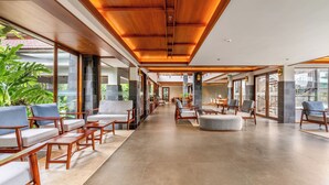 A spacious lobby with wooden ceiling beams, seating areas, and large windows offering views of greenery. - Sterling Lontano Waterfront Wayanad (Sulthan Bathery)