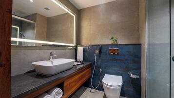 Een moderne badkamer met een grote spiegel, een wastafel op een voet, een toilet en een douchehoek.