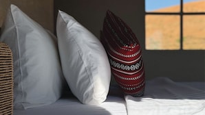 A bed with white bedding and a patterned pillow. - Rahalla Luxury Stay (Bidiya)