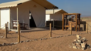 A desert tent with a wooden structure, possibly a play area, and a pile of rocks. - Rahalla Luxury Stay (Bidiya)