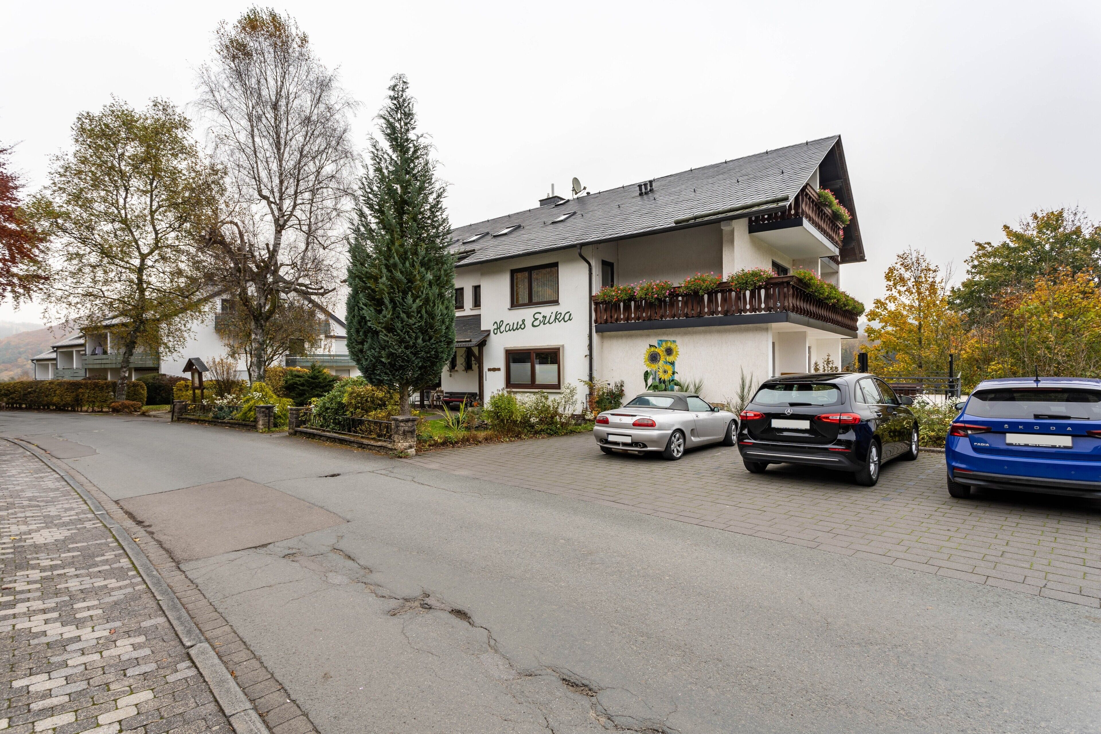 A building with a sign 'Klaus Erika' and two parked cars.