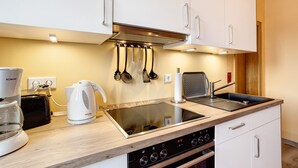 Una cocina moderna con armarios blancos, estufa integrada, cafetera y tostadora.