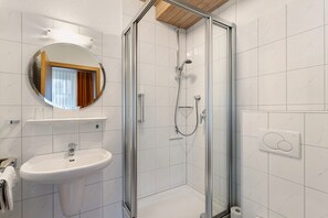 Ein Badezimmer mit Duschkabine, Waschbecken und Spiegel.