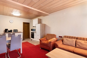 Une pièce compacte comprenant un coin cuisine, un espace repas avec des chaises, un canapé et une table en bois.
