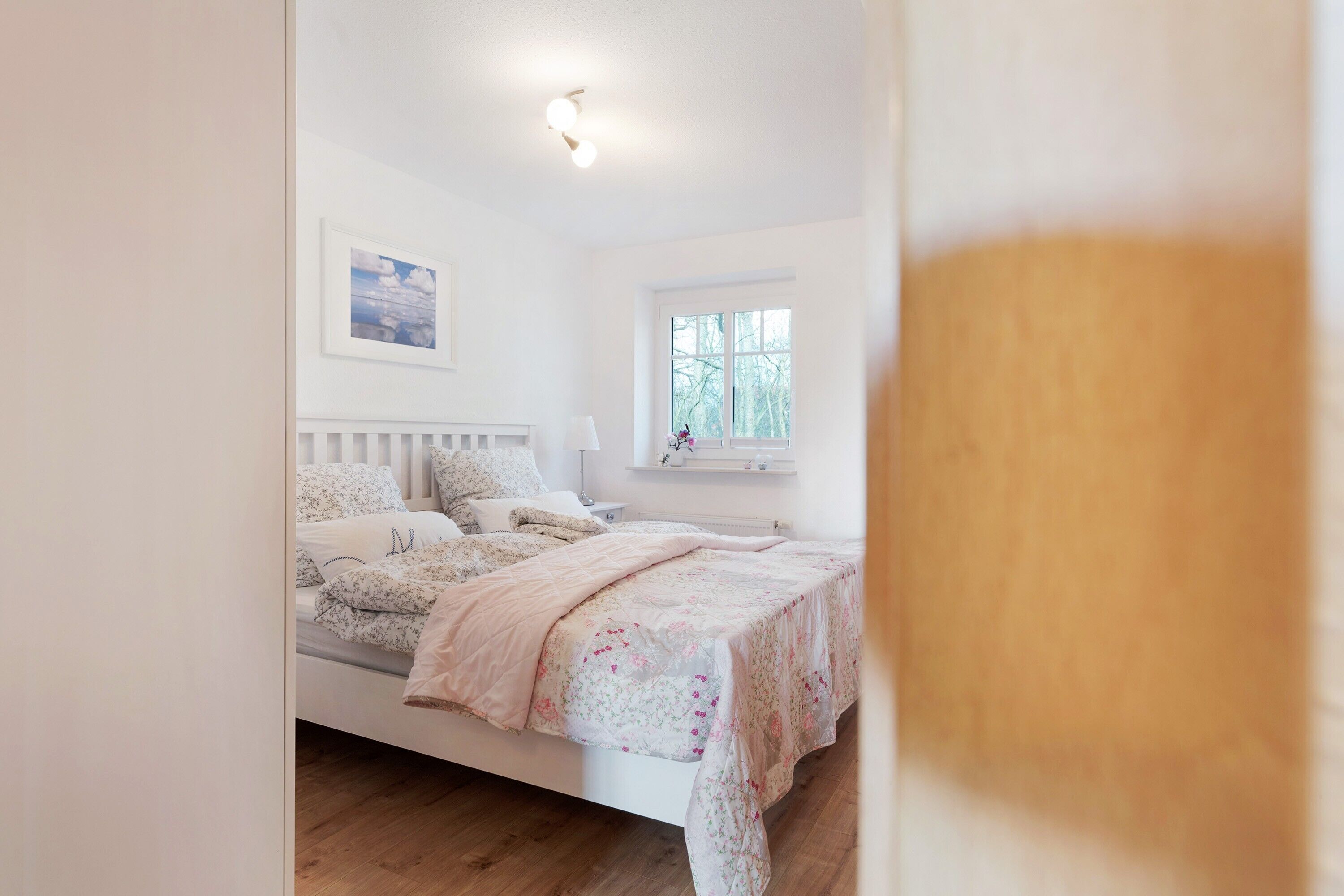 Ein Schlafzimmer mit einem Bett, einem Fenster und einem Wandbild.