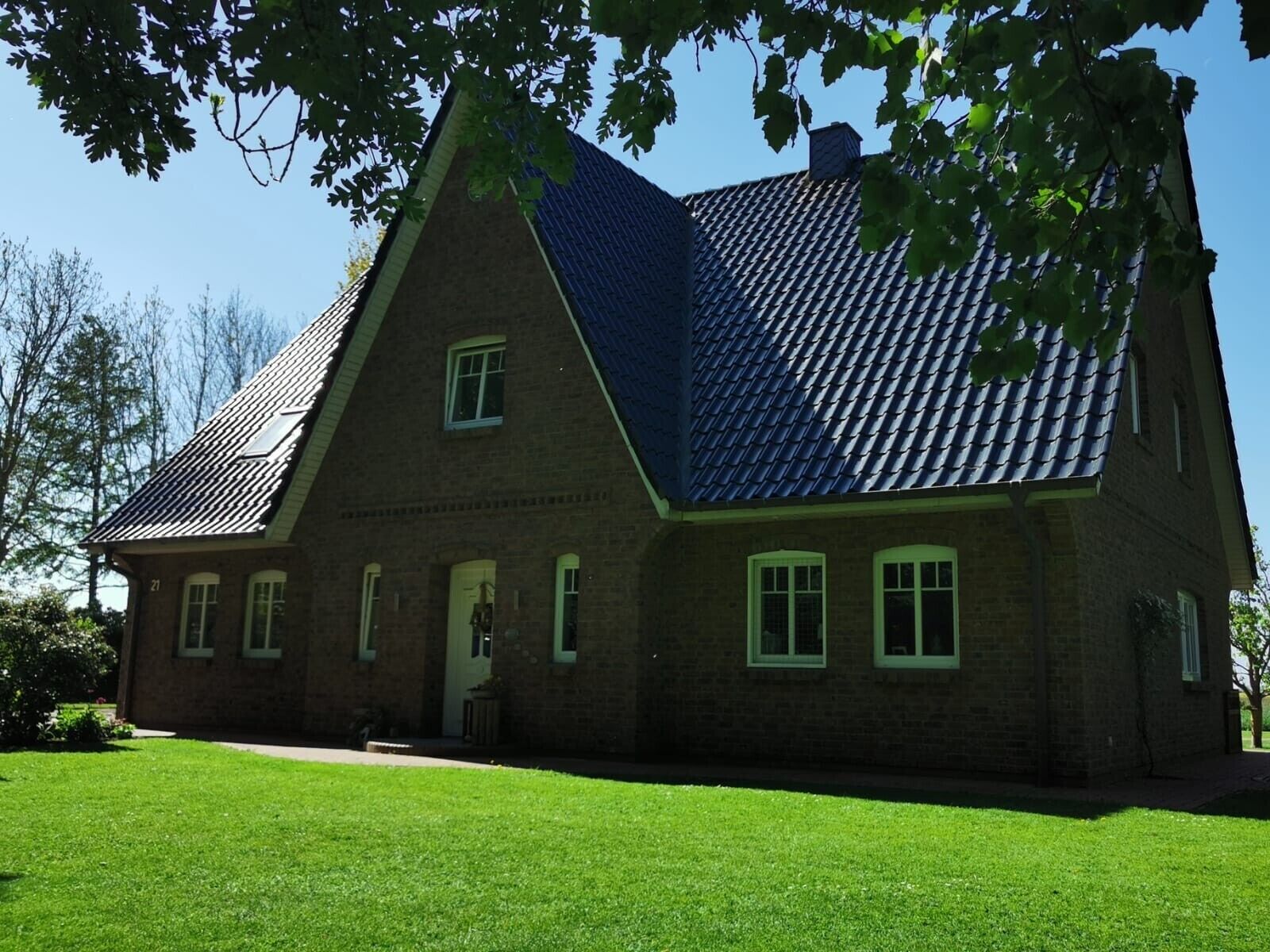 A large brick house with a steeply pitched roof, multiple windows, and a well-maintained lawn.