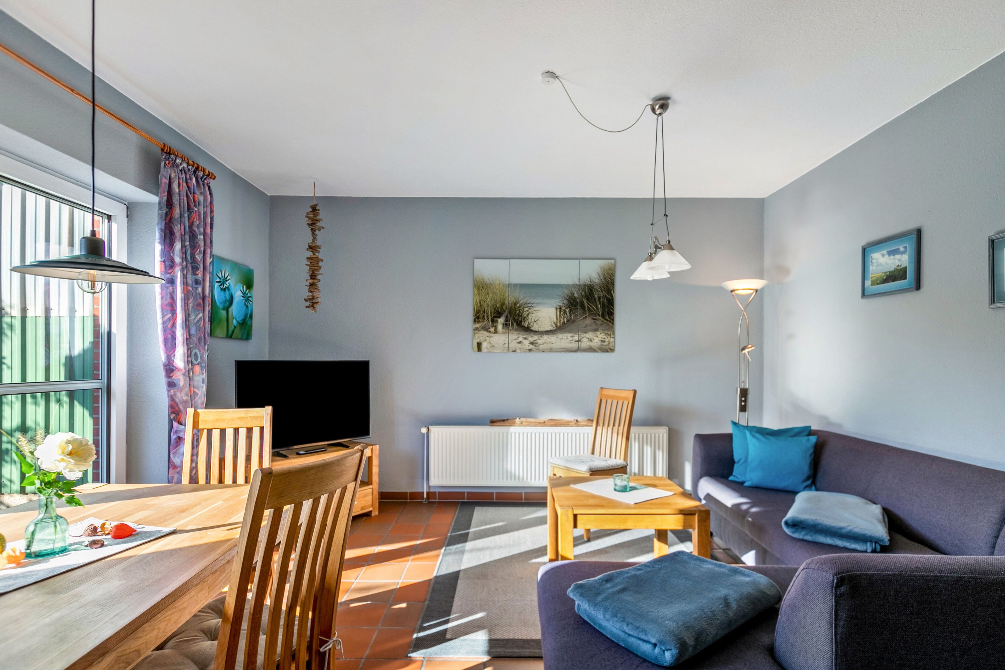 A modern living room with a sofa, TV, dining table, chairs, and a fireplace.