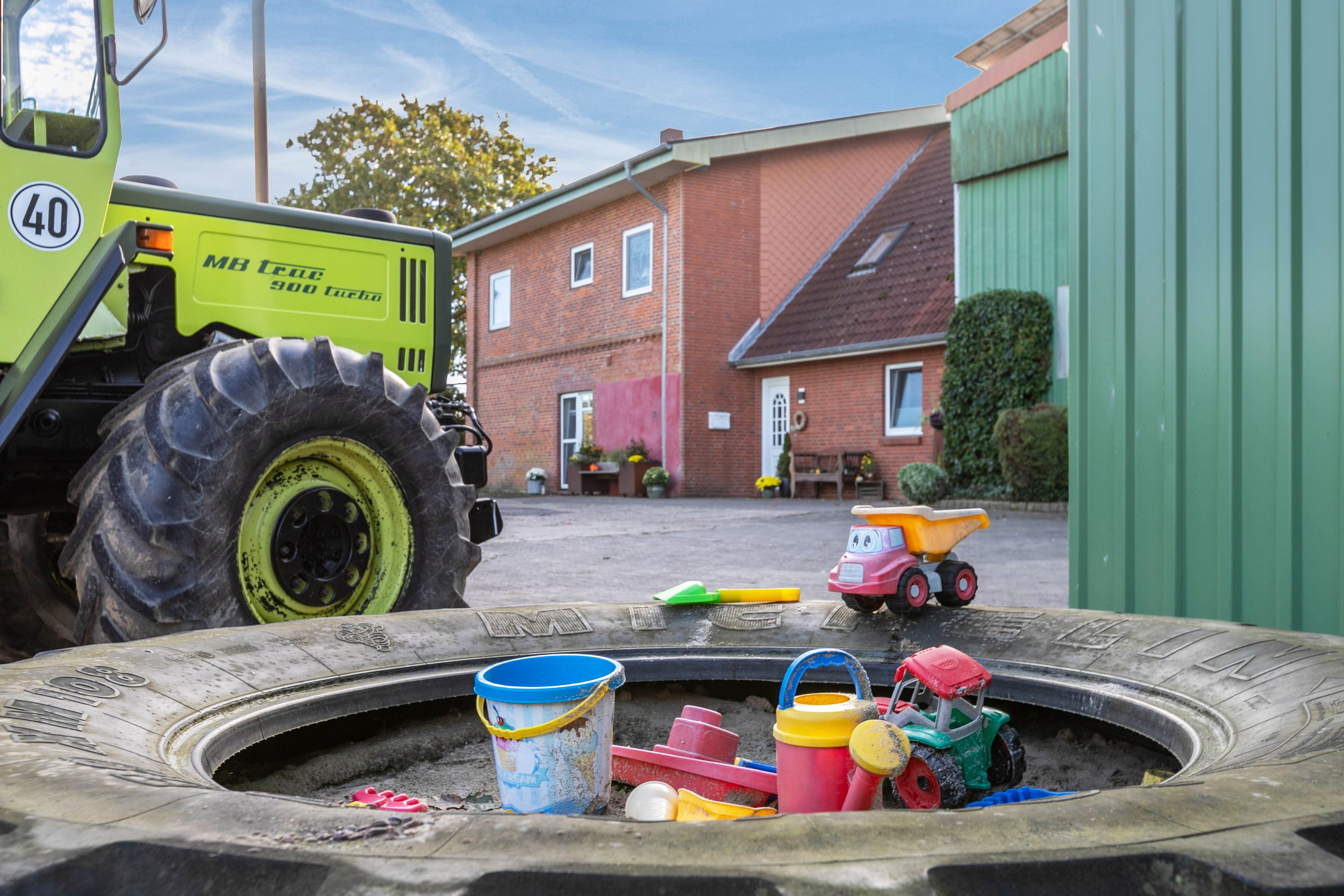 A large industrial vehicle parked in a yard with a small children's play area in the foreground.