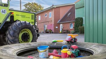 A large industrial vehicle parked in a yard with a small children's play area in the foreground.