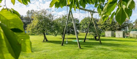Un espacio al aire libre con césped, columpios y árboles.