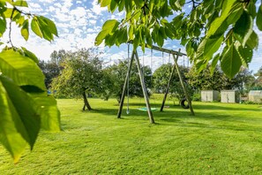 Un espacio al aire libre con césped, columpios y árboles.
