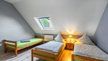 Une chambre de dortoir avec deux lits superposés en bois, une petite table, une lampe et une fenêtre donnant sur un paysage agréable.